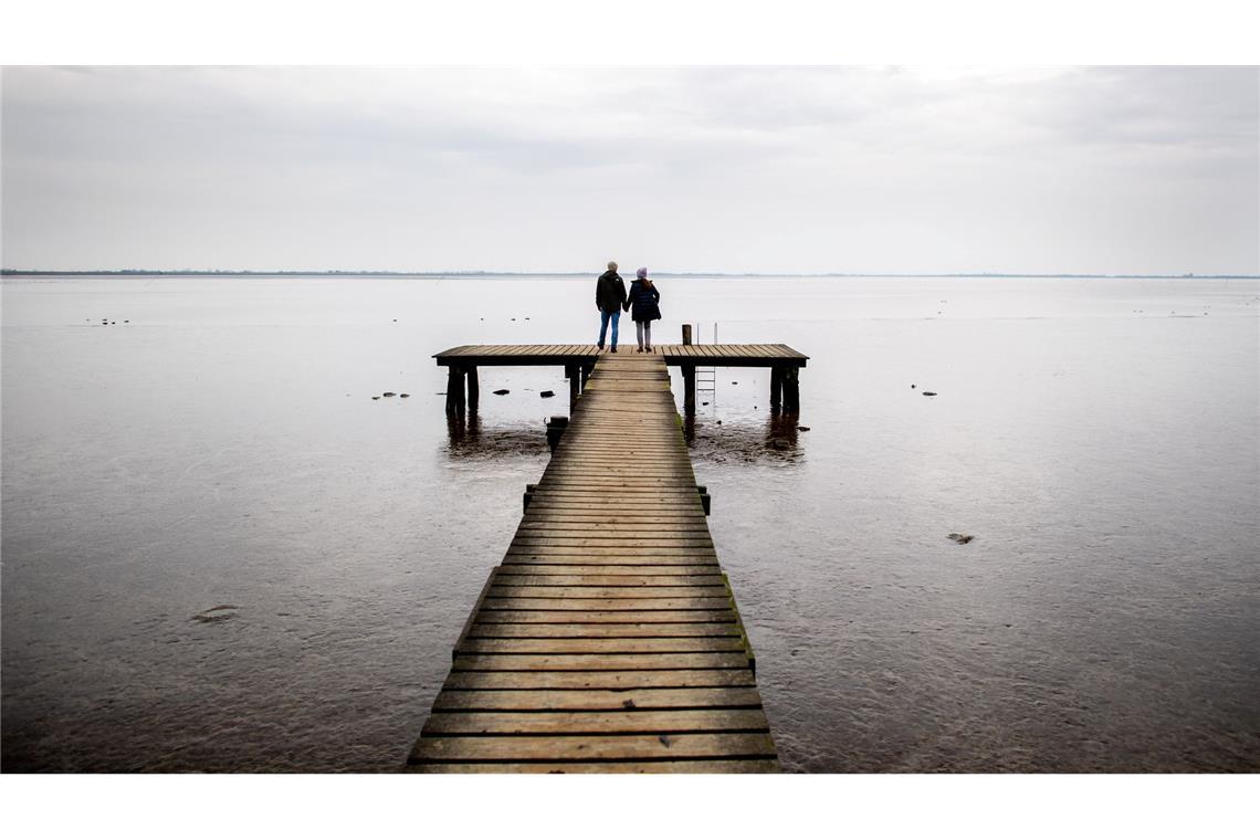 Bilder des Tages Zweisamkeit: Ein Paar geht bei trübem Wetter über einen Holzsteg am Jadebusen im niedersächsischen Dangast.
